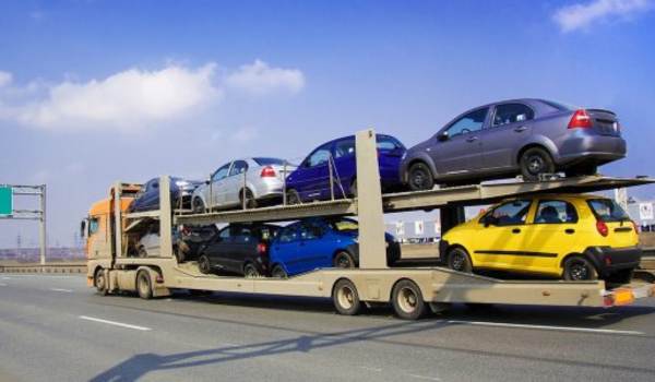 Seattle car shipping work: Open car transport truck carrying multiple vehicles on a highway for delivery.